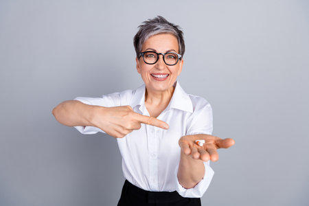 Photo portrait of attractive pensioner woman hold point pills meds dressed stylish formalwear isolated on gray color backgroundの写真素材