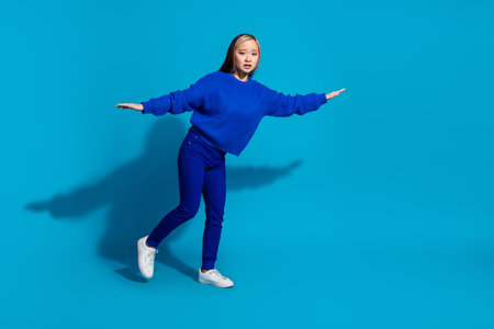 Full length body photo funny youth philippine girl with dyed hairstyle flying two arms wings isolated on blue color backgroundの写真素材