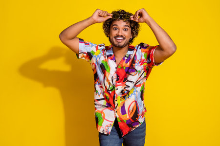 Portrait of nice young man touch sunglass wear shirt isolated on yellow color background