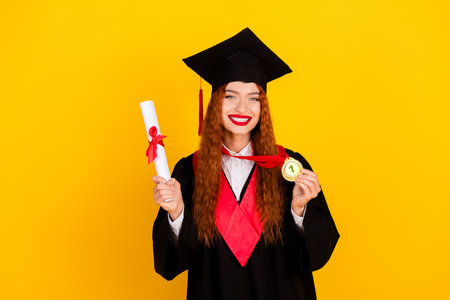 Photo of adorable pretty nice girl wear black mantle hold medal isolated on yellow color backgroundの写真素材
