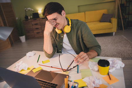 Photo of stressed depressed man sit table work from home apartment workplace workspace evening light...