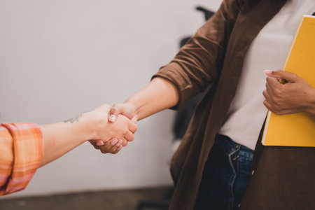 Cropped portrait of two young corporate girls handshake coworking loft interior business center...