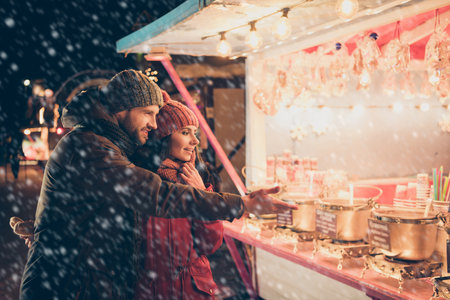 Nice attractive charming lovely cheerful couple wearing warm outfit spending December winter vacation visiting international festival buying goods souvenirs things for family at street saleの写真素材