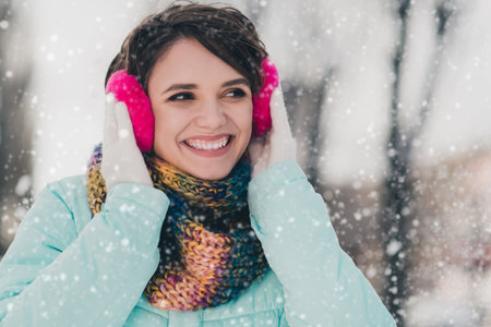 Photo of charming happy nice young woman look away walk winter forest wear earmuffs outdoors outsideの写真素材
