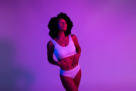 Photo of stunning young model woman closed eyes arms touch tummy underwear isolated on violet neon backgroundの写真素材