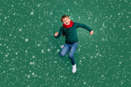 Photo of sweet pretty schoolboy dressed green sweater jumping high smiling isolated green color backgroundの写真素材