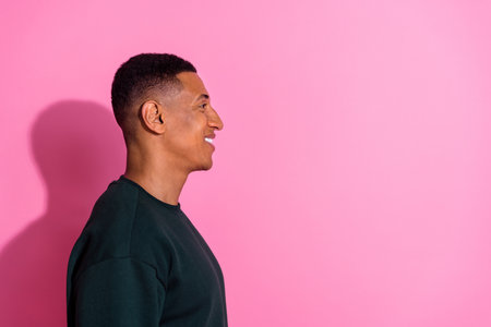 Photo of cheerful positive guy dressed pullover smiling emtpy space isolated pink color backgroundの写真素材