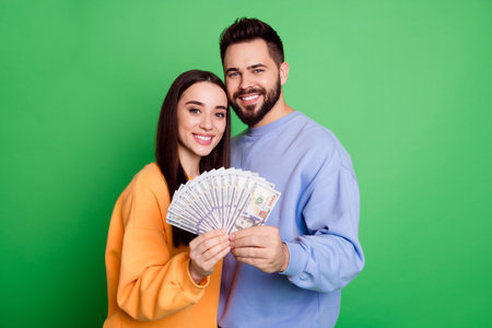 Photo of happy charming couple married people wear stylish clothes hold family budget isolated on green color backgroundの写真素材