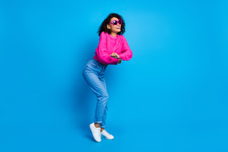 Full length photo of lovely young lady dance have fun dressed stylish pink garment isolated on blue...