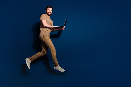 Photo of mature age senior javascript programmer man with laptop working jumping hurry up isolated on dark blue color backgroundの写真素材