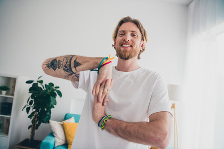 Photo of nice young man stretching wrists arms wear stylish pajama modern light cozy interior flat indoorsの写真素材