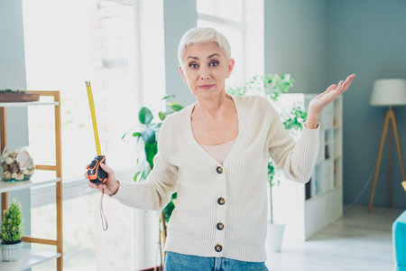 Photo of funny retired woman hold measuring centimeter tape relocation new apartment home house...
