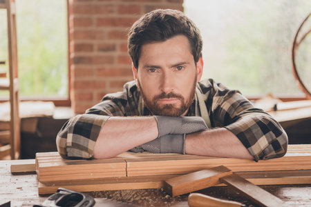 Portrait of handsome bearded master man restoration engineer folded hands sitting at his garage working with wooden constructionsの写真素材