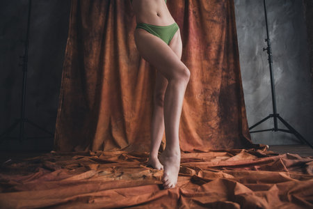 Photo of young charming lady posing nylon tights in studio on brown color backgroundの写真素材