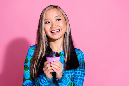 Photo of cheerful pretty lady dressed blue shirt enjoy coffee looking empty space isolated pink...