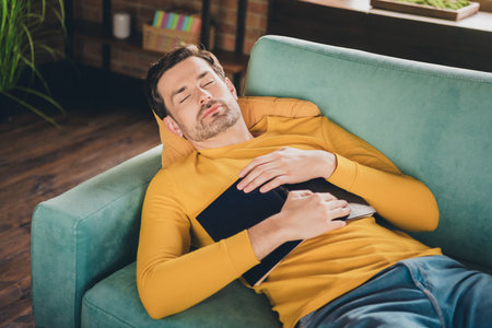 Photo portrait of nice young man sleeping read book closed eyes lying couch wear yellow clothes...