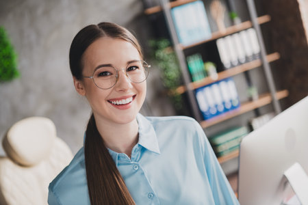 Photo of sweet charming lady assistant wear shirt glasses smiling indoors workplace workstation