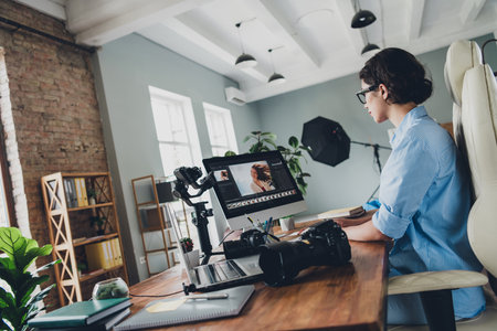 Photo of positive lady photographer dressed shirt retouching portraits modern device indoors...