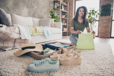 Photo of cheerful good mood lady wear casual t-shirt packing clothes summer vacation indoors room...