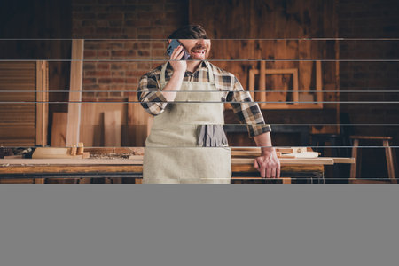 Photo of happy guy using cell smart phone call in garage workshopの写真素材