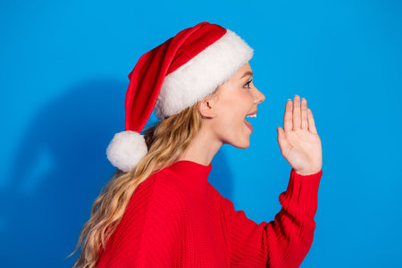 Photo of lovely teen lady share secret profile empty space dressed red christmas garment celebrate winter holidays on blue color backgroundの写真素材
