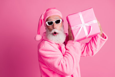 Photo of isolated on impressed funky man hold giftbox christmas time headwear coat pink color backgroundの写真素材