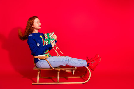 Full length photo of lovely young lady ride sledge giftbox dressed blue christmas garment celebrate...