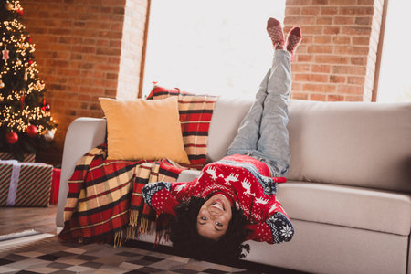 Full body photo of young girl lying sofa upside down wear red christmas clothes enjoy cozy x-mas party decoration interior flat indoorsの写真素材