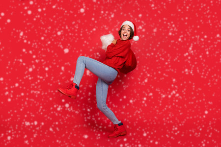 Full length body size photo happy woman in headwear carrying sack with xmas gifts isolated vivid red...