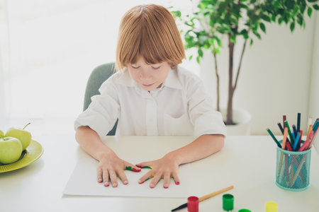 Portrait of cute pretty boy son wearing white shirt painting picture own room modern interior indoorsの写真素材