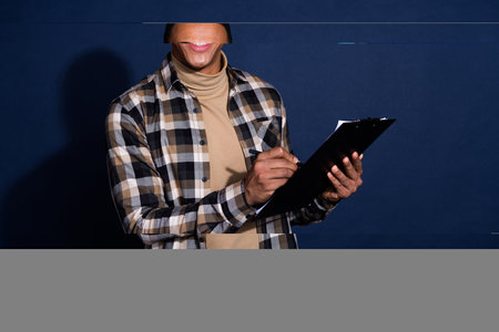 Photo of cheerful positive guy dressed plaid shirt signing contract emtpy space isolated blue color...