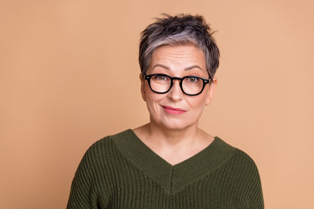 Photo of unsure woman with short hairdo dressed khaki knit sweater in glasses raising eyebrow up...