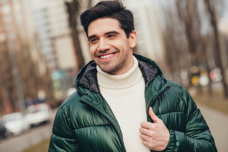 Photo of cheerful attractive man walking on city street excursion in cold autumn weather outdoorsの写真素材
