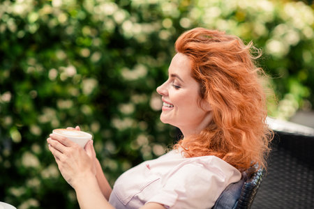 Profile portrait of pretty young woman drink fresh coffee wear t-shirt pastime fresh air street cafe park outdoorsの写真素材