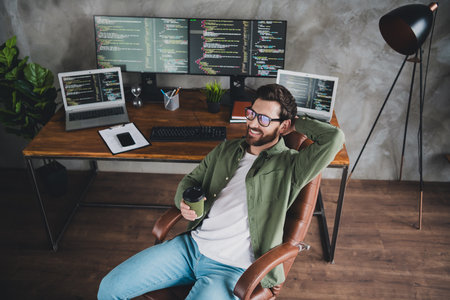 Above view portrait of professional hacker young man drink coffee computer desk loft interior office indoorsの写真素材