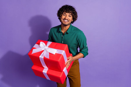 Photo of funny latin man with wavy haircut wearing casual shirt preparing pile giftboxes for birthday isolated on violet color backgroundの写真素材