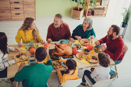 Photo of charming happy big family celebrating thanksgiving day sitting eating lunch traditional meat indoors room homeの写真素材