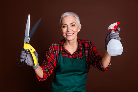 Photo of lovely cheerful woman employee wear workwear hold equipment isolated on brown color backgroundの写真素材