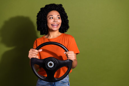 Portrait of nice young woman wheel look empty space wear orange t-shirt isolated on khaki color backgroundの写真素材