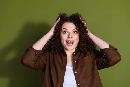 Photo of lovely young woman arms touch head wear brown shirt isolated on khaki color backgroundの写真素材