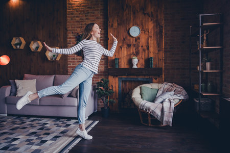 Full size photo of nice teen woman have fun dancing wear stylish striped clothes modern light cozy interior flat indoorsの写真素材