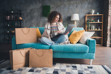 Photo of charming lovely adorable cute woman dressed stylish clothes sitting on soft sofa in cosy apartment indoorsの写真素材