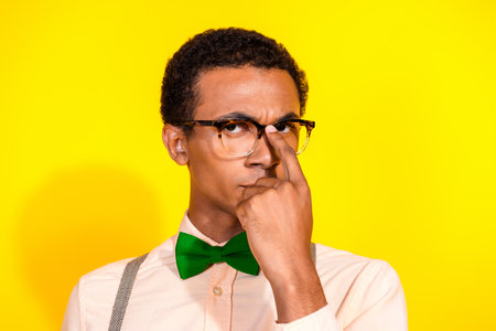 Portrait of attractive classy young man finger fix eyewear wear shirt bow tie isolated on yellow...