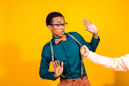 Photo of elegant young man wear shirt bow tie person arm pull suspenders fight isolated on yellow color backgroundの写真素材