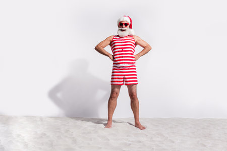 Photo of positive santa claus wear red striped bodysuit relax rest tropical beach isolated on white color backgroundの写真素材