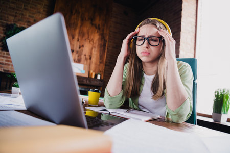 Photo of tired upset lady broker wear shirt eyeglasses headphones feeling tired working modern device indoors workplace workshopの写真素材