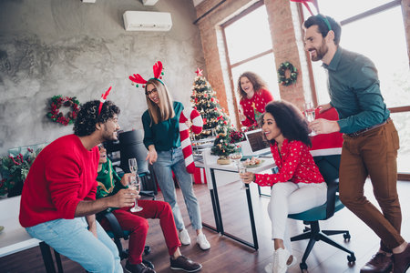 Full size photo of young people team employees have fun celebration enjoy cozy christmas decoration interior office indoors corporate party