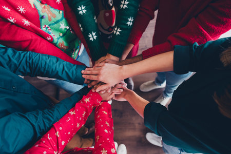 Cropped photo of cheerful young people colleagues hold hands circle teamwork cozy christmas party decor spacious office indoorsの写真素材