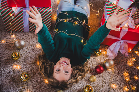 Photo of cheerful teen girl lying floor welcome dressed green christmas garment tradition atmosphere decor vibe house indoors roomの写真素材