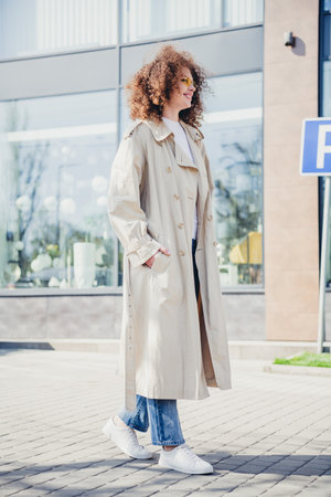 Vertical photo of stunning cheerful girl wear stylish beige trench spring season sunny weather outdoorsの写真素材